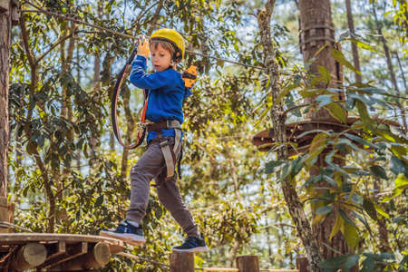Happy child in a helmet, healthy teenager school boy enjoying activity in a climbing adventure park on a summer dayの写真素材