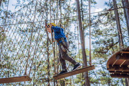 Happy child in a helmet, healthy teenager school boy enjoying activity in a climbing adventure park...