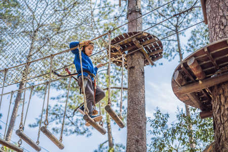 Happy child in a helmet, healthy teenager school boy enjoying activity in a climbing adventure park on a summer dayの写真素材