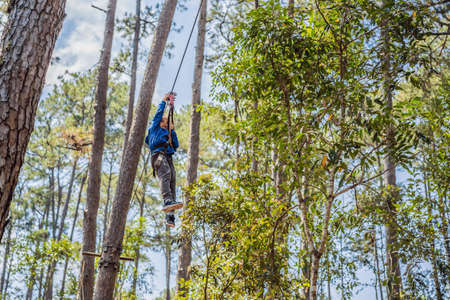 Happy child in a helmet, healthy teenager school boy enjoying activity in a climbing adventure park...