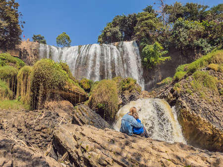Mother and son tourists on the background of Elephant waterfall near Dalat city in Vietnamの写真素材