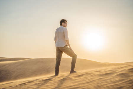 Man traveling in the desert. Sandy dunes and blue sky on sunny summer day. Travel, adventure, freedom concept.の写真素材