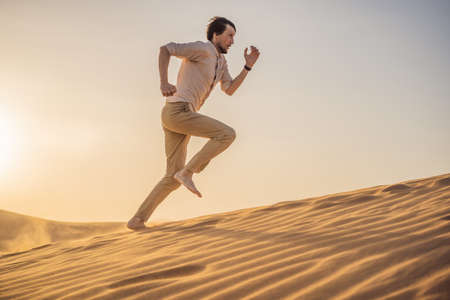 The person overcomes difficulties and aspires to the purpose and dream. A man overcomes difficulties in life as if in a desertの写真素材