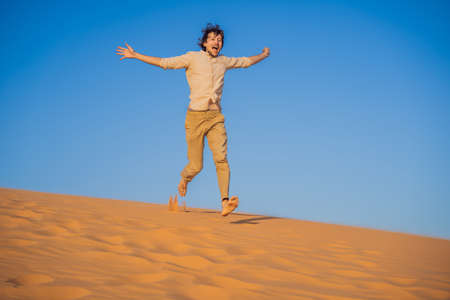 Man traveling in the desert. Sandy dunes and blue sky on sunny summer day. Travel, adventure, freedom concept.の写真素材