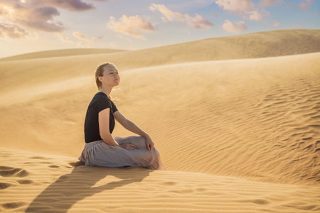 Young beautiful woman traveling in the desert. Sandy dunes and blue sky on sunny summer day. Travel, adventure, freedom concept. Tourism reopens after quarantine COVID 19の写真素材