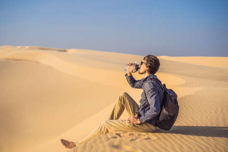 Man feels thirst and drinks water in the desertの写真素材