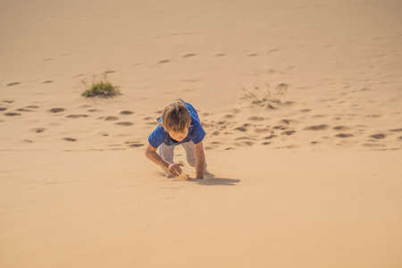 Boy overcomes difficulties and aspires to the purpose and dream. Boy overcomes difficulties in life as if in a desertの写真素材