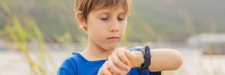Boy uses kids smart watch outdoor against the background of the garden BANNER, LONG FORMATの写真素材