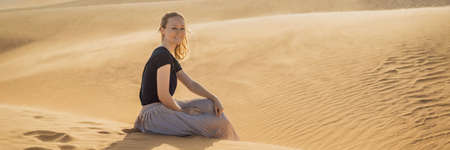 Young beautiful woman traveling in the desert. Sandy dunes and blue sky on sunny summer day.の写真素材