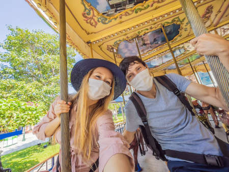 Man and woman wearing a medical mask during COVID-19 coronavirus at an amusement parkの写真素材