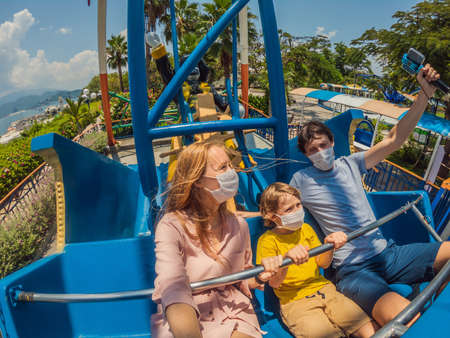 Family wearing a medical mask during COVID-19 coronavirus at an amusement parkの写真素材