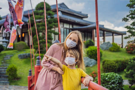 Mother and son travelers in medical mask looking at the Japanese traditional building.の写真素材