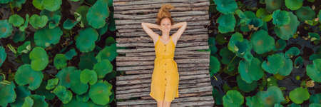 Young woman in a yellow dress on the path among the lotus lake. Mua Cave, Ninh Binh, Vietnam.の写真素材