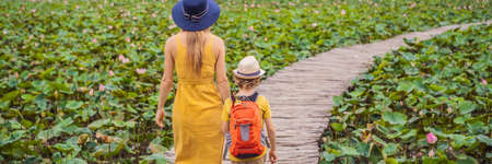 Mother and son in a yellow on the path among the lotus lake. Mua Cave, Ninh Binh, Vietnam.の写真素材