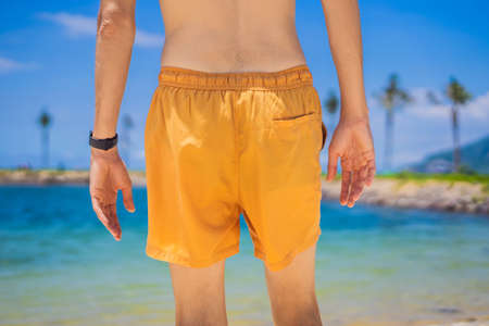 Fashion outdoor image of stylish man walking alone at beautiful beach, enjoy freedom and nice relaxed vacation day tropical beach backgroundの写真素材
