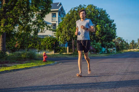 A man runner is engaged in jogging on the asphalt without shoes, without sneakers, for healthの写真素材