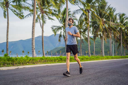 Runner wearing medical mask, Coronavirus pandemic Covid-19. Sport, Active life in quarantine surgical sterilizing face mask protection. Outdoor run on athletics track in Corona Outbreakの写真素材