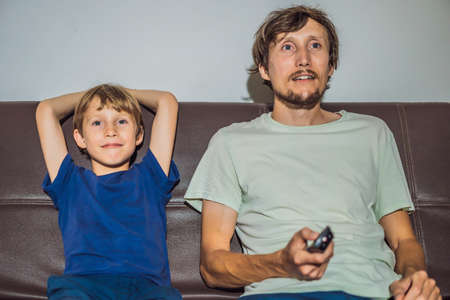Father and son watching TV in evening at home