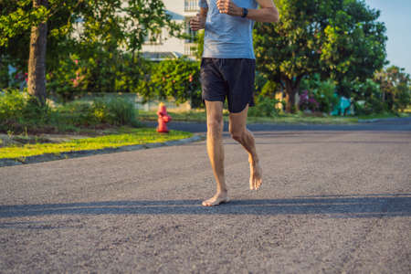 A man runner is engaged in jogging on the asphalt without shoes, without sneakers, for health
