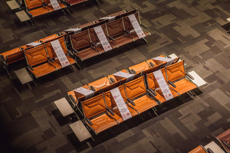 31.05.2021, Doha, Qatar: Socia distancing sign at airport seat, new normal concept. Deserted airport departure lounge in Qatar, UAEのeditorial素材