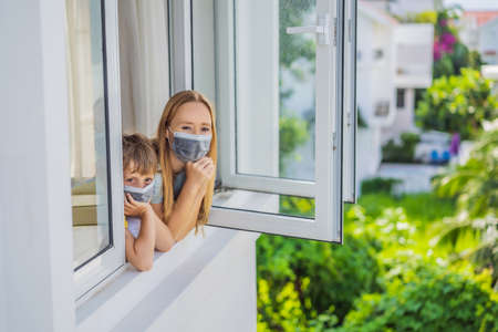 Extremly tired Mother and son looking out the window, home alone. self-isolation at home, quarantine...