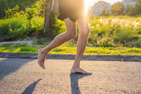 A man runner is engaged in jogging on the asphalt without shoes, without sneakers, for healthの写真素材