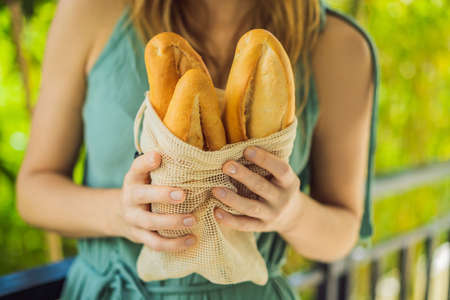 Reusable grocery bags with bread in the hands of a young woman. Zero waste shopping. Zero waste conceptの写真素材