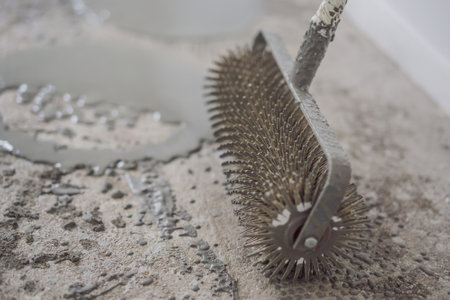 plasterer during floor covering works with self-levelling cement mortar, uses a needle rollerの写真素材