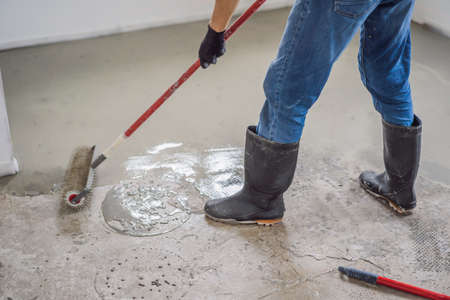plasterer during floor covering works with self-levelling cement mortar, uses a needle rollerの写真素材