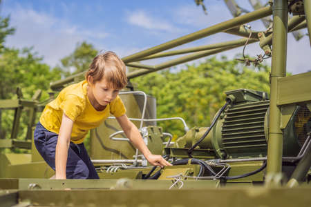 A little boy is studying military equipment. No war