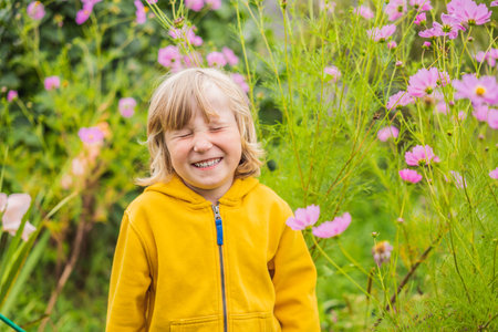 Boy enjoying pink flowers in the gardenの写真素材