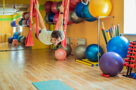 Young man practicing aerial yoga in gym. Lifestyleの写真素材