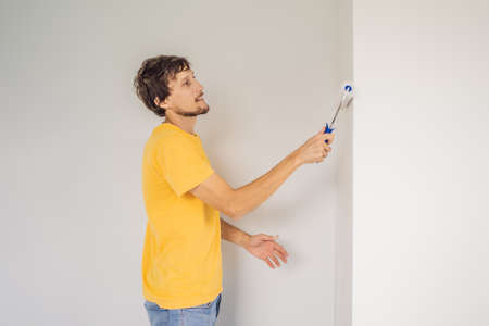One male house painter worker painting and priming wall with painting roller. DIYの写真素材