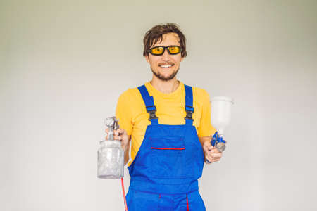 Painter in work clothes with a paint spray gun