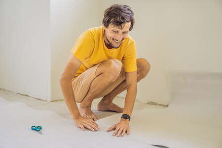 man and a roll of insulating cloth to install a laminate wooden floor