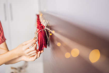Woman making Christmas advent calendar. Pouches on a rope