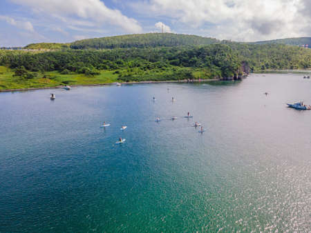 Many Persons stand up paddle boarding on a flat warm quiet sea with beautiful sunset colors