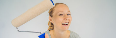 Woman house painter worker painting and priming wall with painting roller. DIY BANNER, LONG FORMATの写真素材