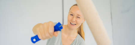 Woman house painter worker painting and priming wall with painting roller.の写真素材