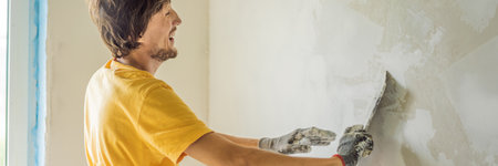Plasterer home improvement handyman worker with putty knife working on apartment wall filling BANNER, LONG FORMATの写真素材