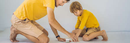 BANNER, LONG FORMAT Dad and son are laying floor insulation. Roll of insulating cloth to install a laminate wooden floorの写真素材