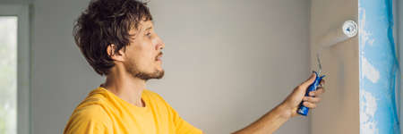 One male house painter worker painting and priming wall with painting roller. DIY BANNER, LONG FORMATの写真素材