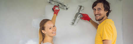 A man and a woman are plastering the walls of the house. DIY home renovation BANNER, LONG FORMATの写真素材