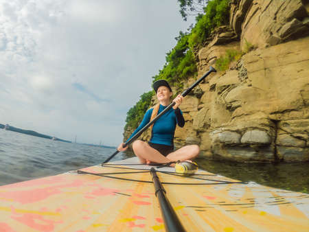 Young women Having Fun Stand Up Paddling in the sea. SUP. Red hair girl Training on Paddle Board...