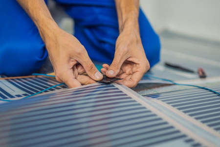 Master installs film warm floor in the room. Floor heating installation