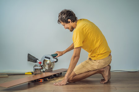 Man installing new wooden laminate flooring on a warm film floor. Infrared floor heating system under laminate floorの写真素材
