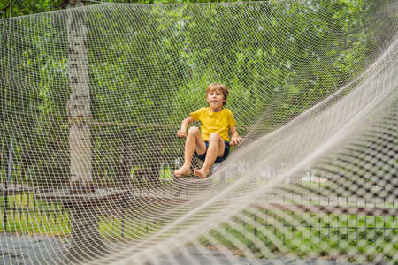 practice nets playground. boy plays in the playground shielded with a protective safety net. concept of children on line, kid in social networks. blurred background, blurred motion due to the conceptの写真素材
