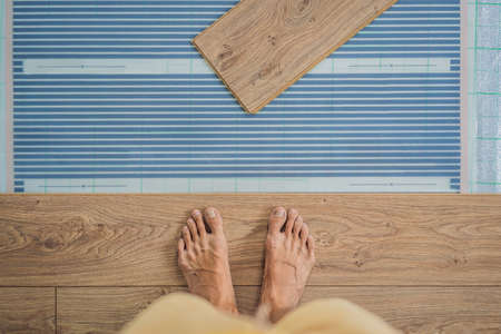 Wooden floor, laminate on a warm film floor. Comfort in home. Warm floor concept. Heating in the...