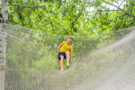 practice nets playground. boy plays in the playground shielded with a protective safety net. concept of children on line, kid in social networks. blurred background, blurred motion due to the conceptの写真素材