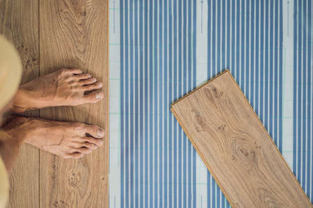 Wooden floor, laminate on a warm film floor. Comfort in home. Warm floor concept. Heating in the house and apartmentの写真素材